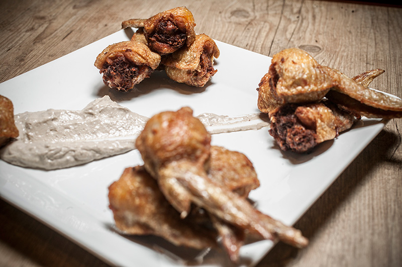 Crocantes, as asinhas de frango recheadas de carne-seca vêm no prato manchado por creme de azeitonas