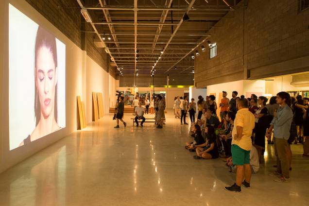 Público assiste um dos vídeos da exposição na noite de abertura do galpão Público assiste um dos vídeos da exposição na noite de abertura do galpão