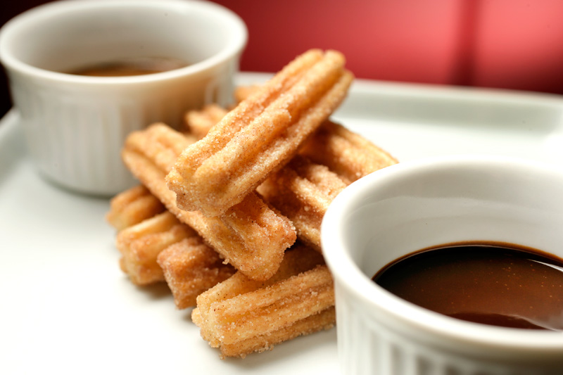 A porção de churros vem à mesa com doce de leite ou chocolate A porção de churros vem à mesa com doce de leite ou chocolate