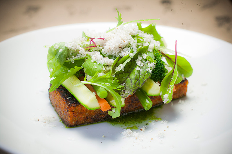 O quibe de quinoa tostado vem coberto por salada