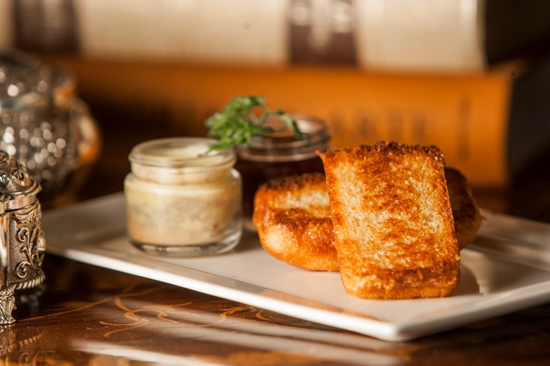 A terrine de foie gras com geleia de frutas vermelhas chega junto de um brioche dourado A terrine de foie gras com geleia de frutas vermelhas chega junto de um brioche dourado