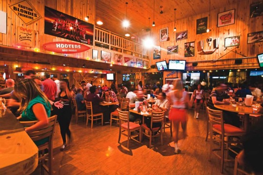 Salão do Hooters: homens são a maioria na happy hour animada com chope em copo ou jarra Salão do Hooters: homens são a maioria na happy hour animada com chope em copo ou jarra