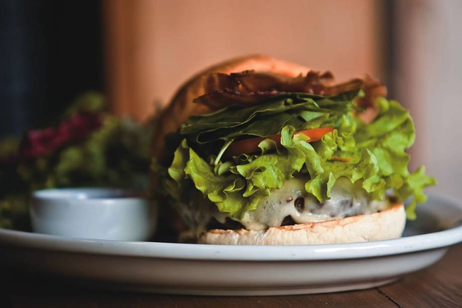 O hambúrguer da casa, com alface, agrião, bacon e molho barbecue O hambúrguer da casa, com alface, agrião, bacon e molho barbecue