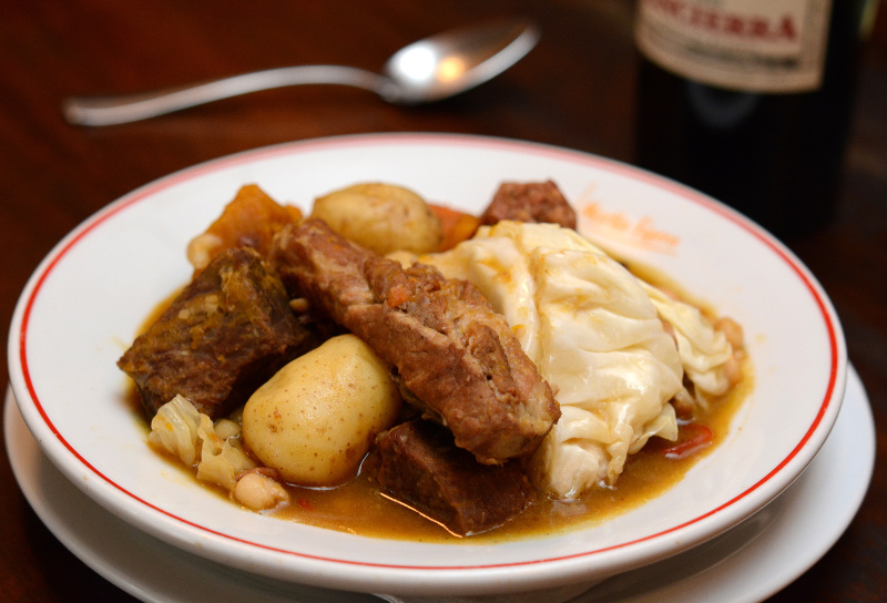 Prato fundo branco com cozido com carne, batata e repolho.