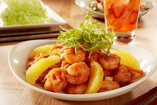 Camarões preparados com molho levemente picante, servidos com gomos de laranja e finalizados com brotos Camarões preparados com molho levemente picante, servidos com gomos de laranja e finalizados com brotos