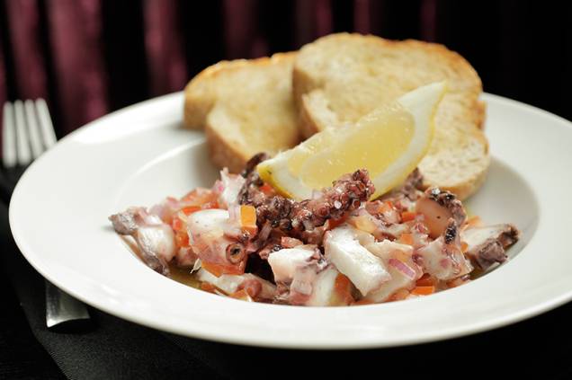 O polvo ao vinagrete de cebola-roxa, tomate e azeite vem com torradas grelhadas O polvo ao vinagrete de cebola-roxa, tomate e azeite vem com torradas grelhadas