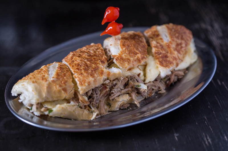 O sanduíche de pernil em lascas, queijo da Serra da Canastra, vinagrete e rúcula na baguete