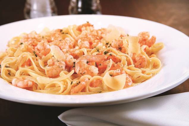 O shrimp linguini alfredo leva camarões assados mergulhados no molho alfredo, com linguini O shrimp linguini alfredo leva camarões assados mergulhados no molho alfredo, com linguini