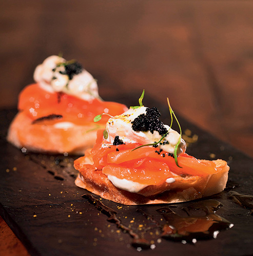 Tapas de salmão defumado servidas sobre fatia de pão ciabatta