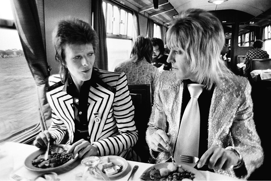 David Bowie e Mick Ronson almoçando em trem, em 1973