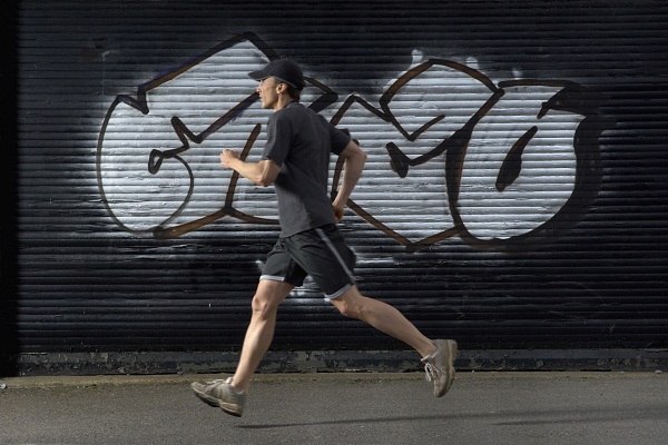 man running past graffitti
