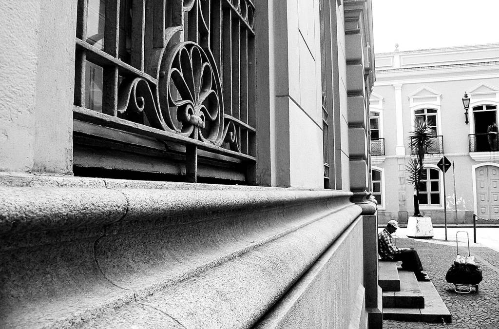 Homem descansa em escada no Pateo do Colegio