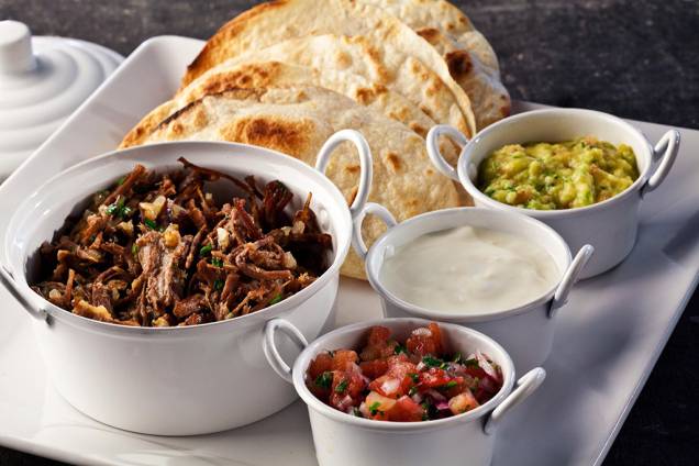 Fajitas mexicanas para serem montadas na mesa vêm com carne desfiada, sour cream, guacamole e salsa pico de galo Fajitas mexicanas para serem montadas na mesa vêm com carne desfiada, sour cream, guacamole e salsa pico de galo