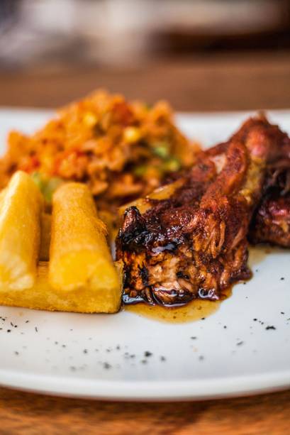 Costelinha de porco com calda de figo ao lado de arroz criollo e mandioca frita