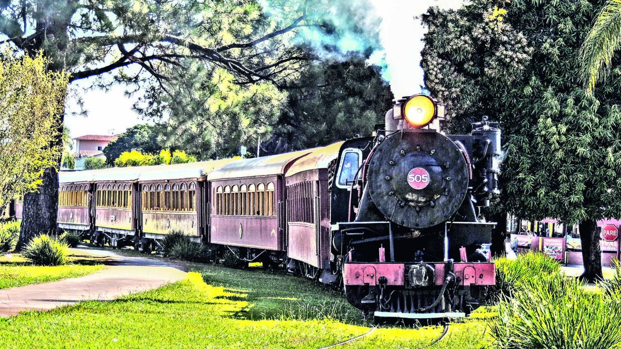 Foto mostra gramado e maria-fumaça preta e vermelha em rota de Campinas e Jaguariúna.