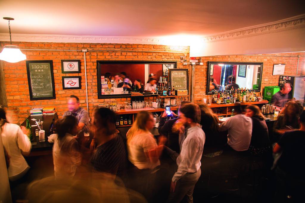 Pessoas reunidas em torno de balcão de bar sob luz amarelada