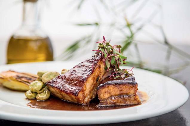 A tenra barriga de porco de pele crocante vem com acelga bok choy, favas e molho de tangerina A tenra barriga de porco de pele crocante vem com acelga bok choy, favas e molho de tangerina