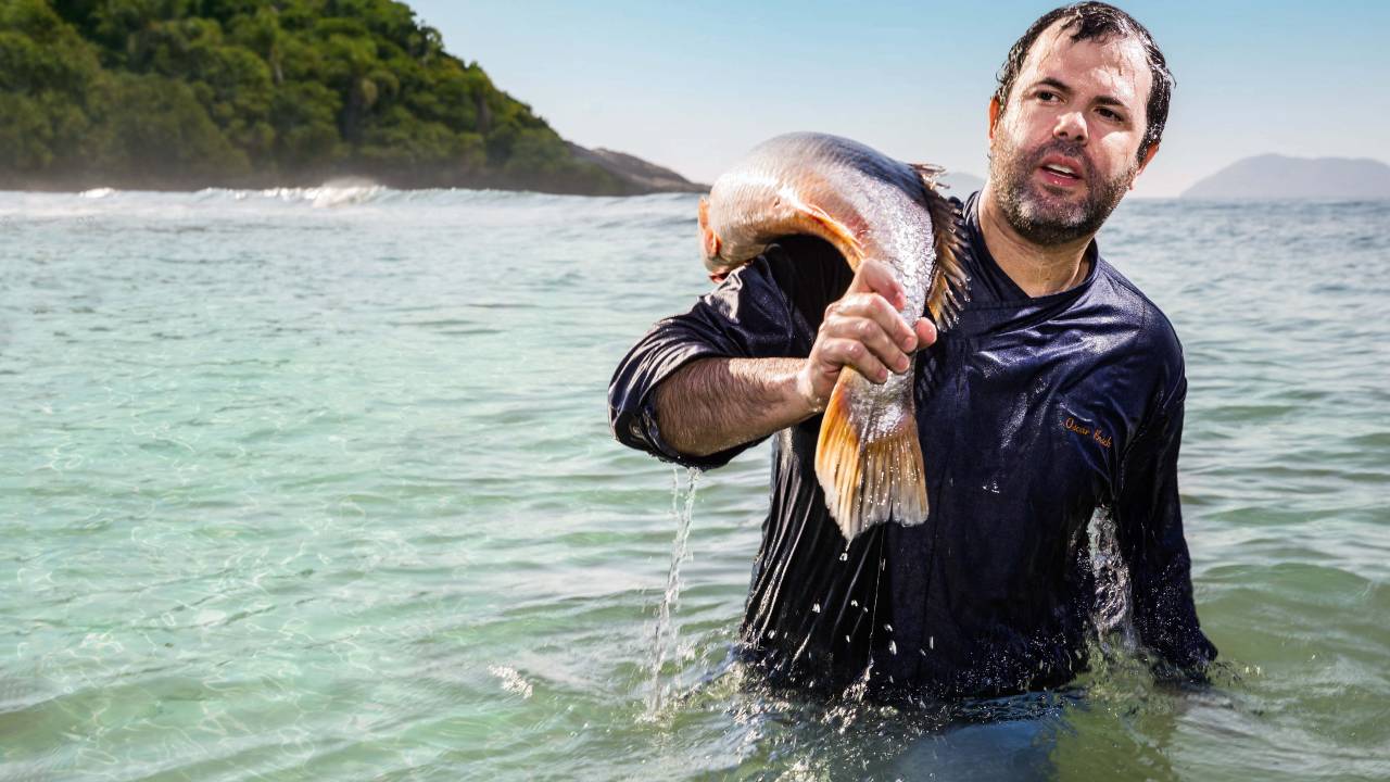 Homem no mar carrega peixe no ombro