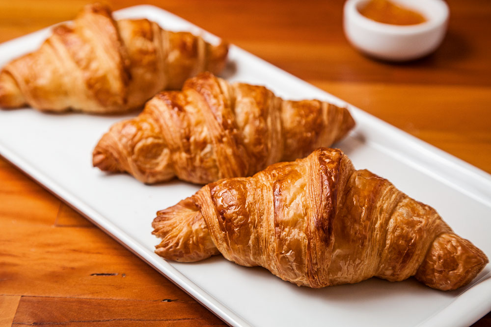 Croissant da padaria Fabrique Pão e Café, em Higienópolis. Três croissants enfileirados em cima de prato branco