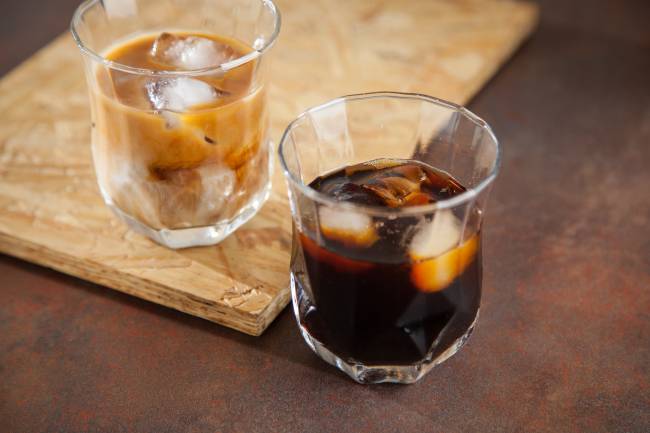 Pato Rei Dois copos de cafés, um à frente escuro e com gelo, o de trás com gelo e leite