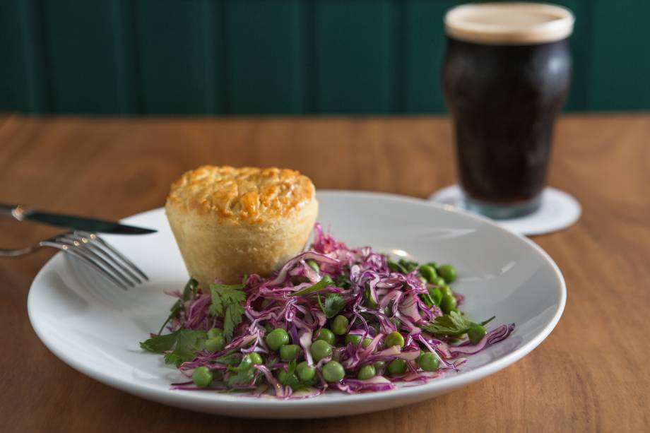 Guinness pie: tortinha que lembra a de empada recheada com picadinho de carne cozida na cerveja preta, acompanhada de salada de repolho-roxo e ervilha Guinness pie: tortinha que lembra a de empada recheada com picadinho de carne cozida na cerveja preta, acompanhada de salada de repolho-roxo e ervilha