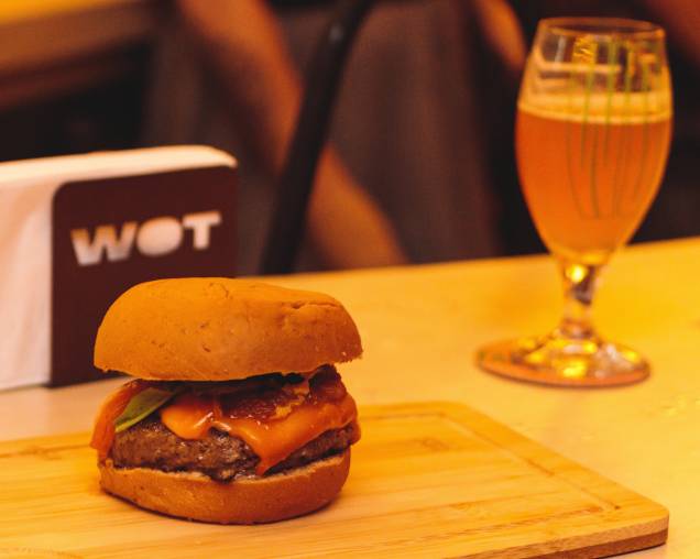 Hambúrguer e cerveja: sanduíche com queijo do tipo cheddar, geleia de bacon, picles de maxixe, rúcula e maionese no pão de cerveja stout e chope IPA Hambúrguer e cerveja: sanduíche com queijo do tipo cheddar, geleia de bacon, picles de maxixe, rúcula e maionese no pão de cerveja stout e chope IPA