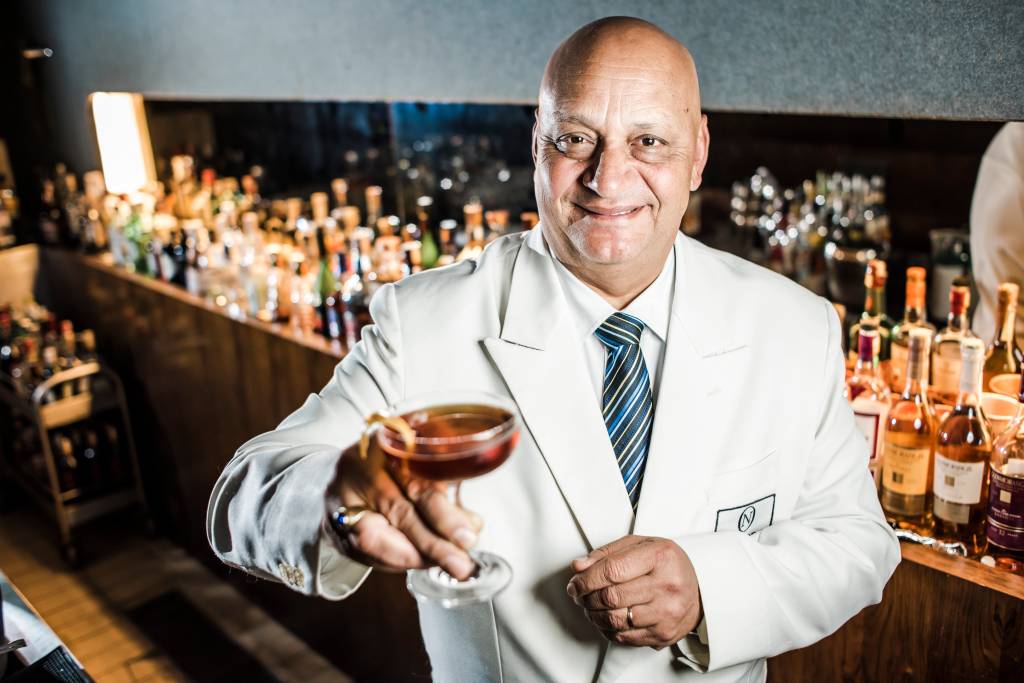 DERIVAN Homem de terno branco segura taça