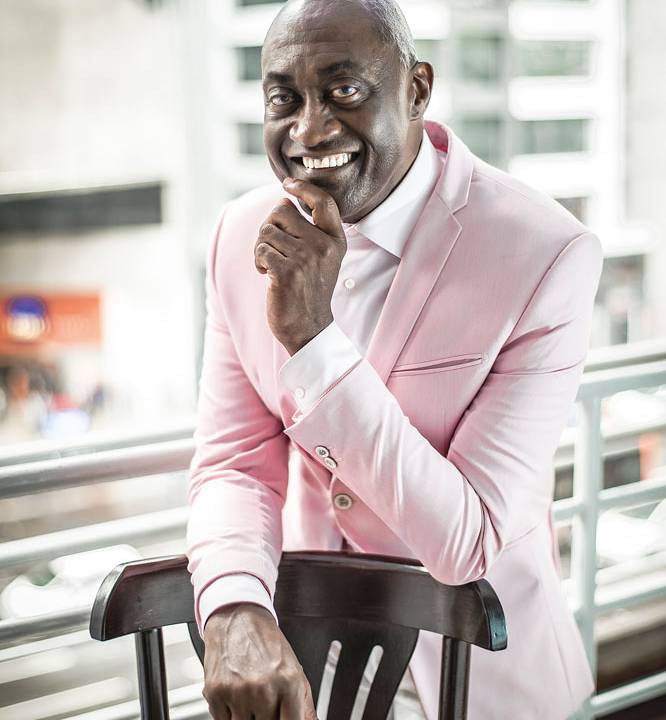 Ismael Ivo posa para a câmera sorrindo; ele veste um terno