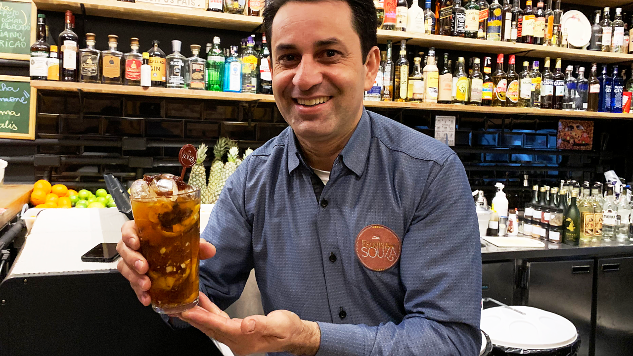 Homem segura caipirinha em bar