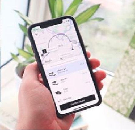 Uma mão segurando um celular. Na tela do equipamento aparece a interface do aplicativo da Uber, com a solicitação de uma viagem