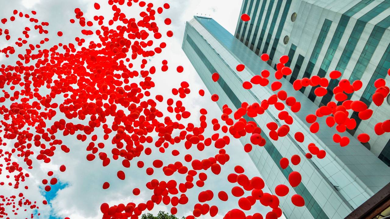 Imagem mostra dezenas de balões vermelhos subindo em direção ao céu ao lado de prédio do Hospital das Clínicas da USP