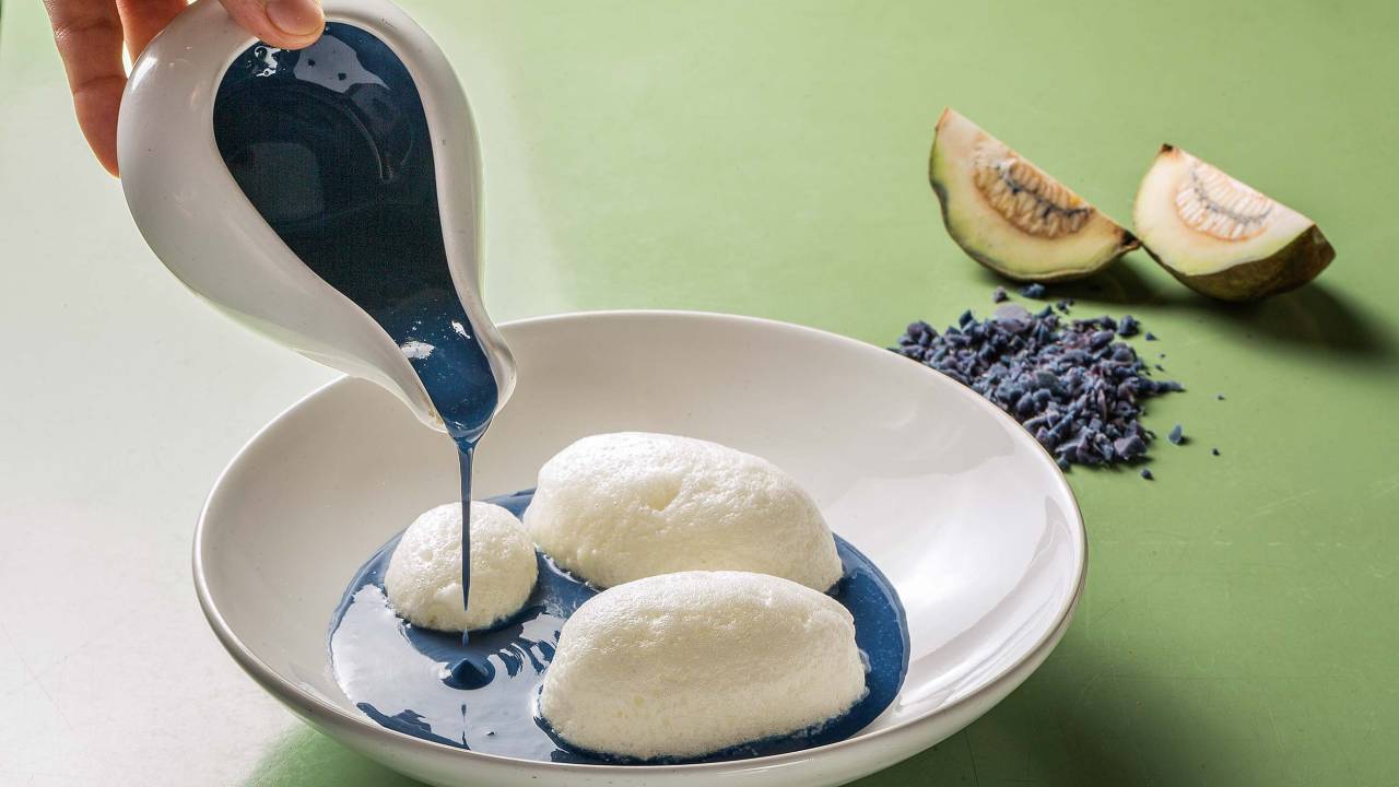 prato branco com bolas brancas de merengue sendo cobertos por creme inglês azul