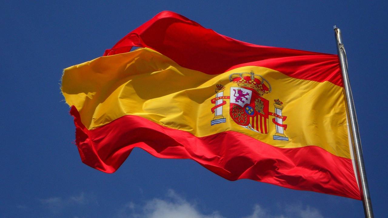 Imagem mostra bandeira da Espanha tremulando com céu ao fundo