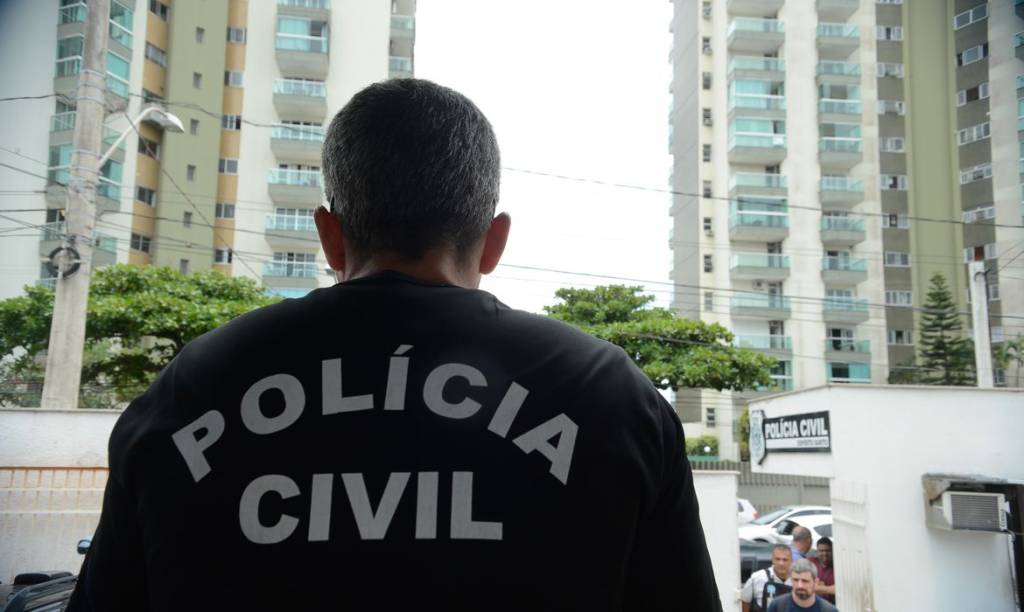 A imagem mostra um Policial Civil de costas