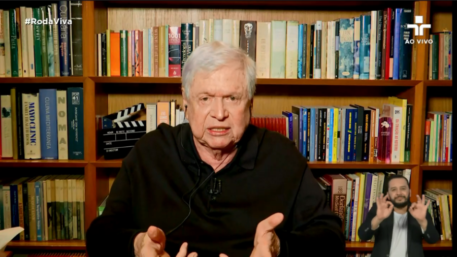 Foto de Boni diante de prateleiras de livros