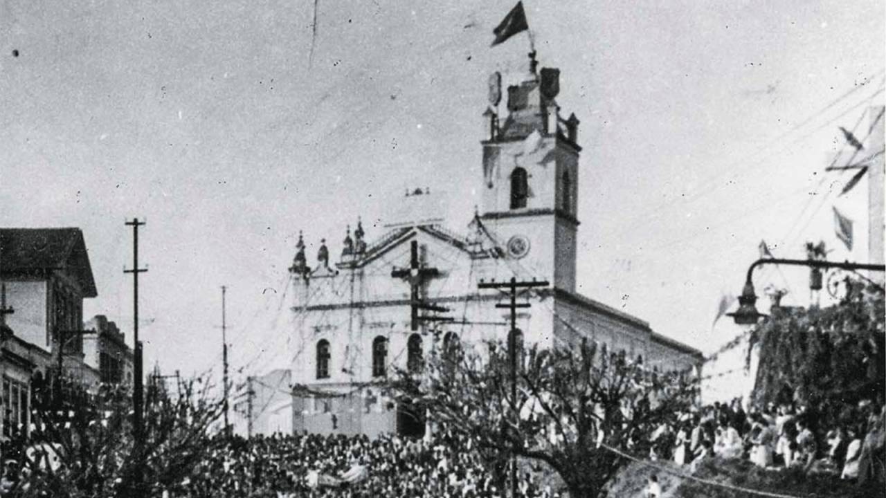 foto em preto e branco da igreja matriz de nossa senhora da penha com procissão à frente