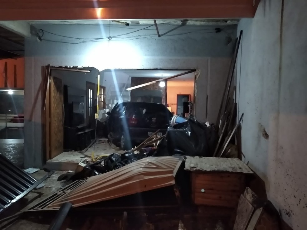 Carro dentro de uma sala. Portão e frente da casa totalmente destruídos