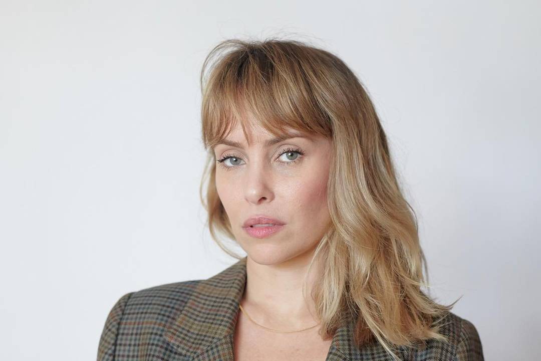 Imagem de Fernanda, de terno, em um fundo branco