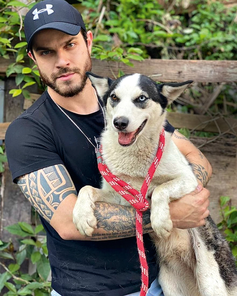 Felipe Becari (REPRODUÇÃO-INSTAGRAM)_1.jpg Vereador Felipe Becari veste boné, camiseta preta e segura cão de médio porte com pelos brancos e pretos na região do rosto e orelhas.