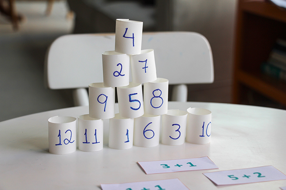 pirâmide números Pirâmide feita com tiras de papel com números escritos. Na mesa, as operações correspondentes a cada linha da pirâmide.