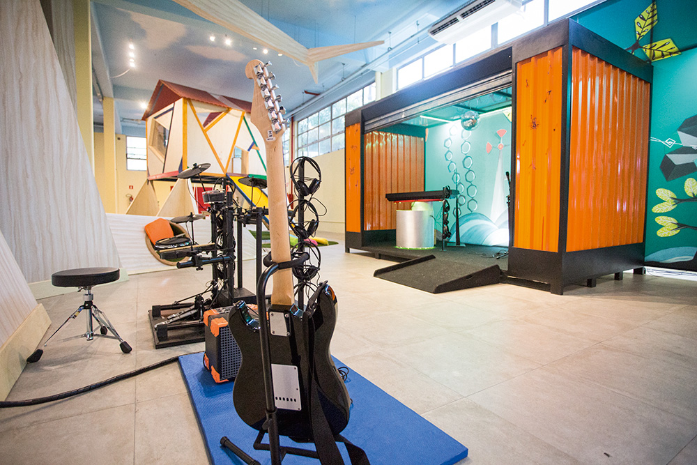 Imagem de um espaço do Museu da Imaginação com uma guitarra, instrumentos musicais e uma casa da árvore