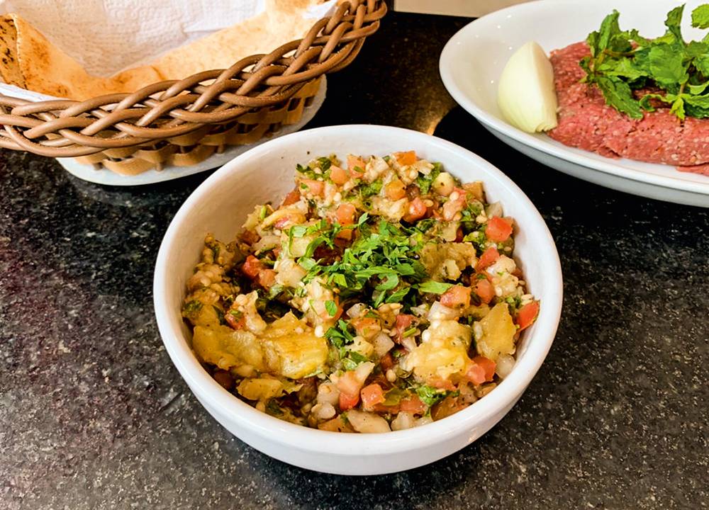 Salada de berinjela: leva a hortaliça assada, tomate, cebola, zátar e salsinha regados de azeite