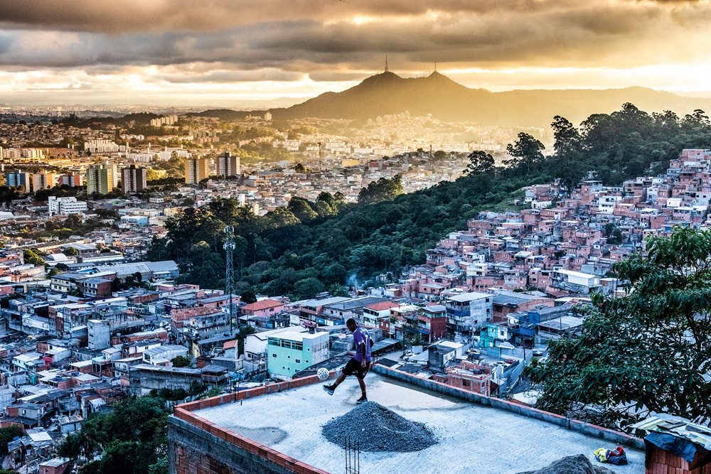Paisagem da ZN, com um homem fazendo uma embaixadinha em cima da laje
