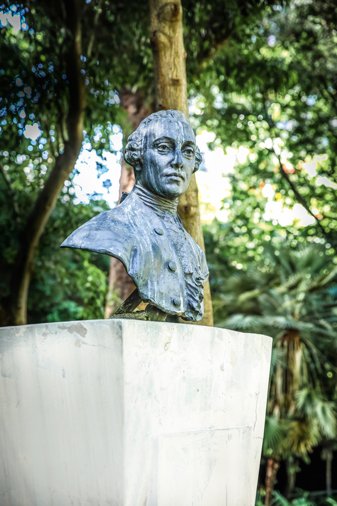 A imagem é um retrato, 3x4, do rosto de Caio. Ele está de terno e sorrindo.