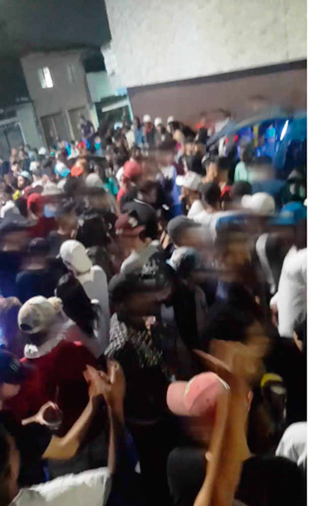 Baile funk com a rua completamente lotada de pessoas, todas sem máscaras e apertadas