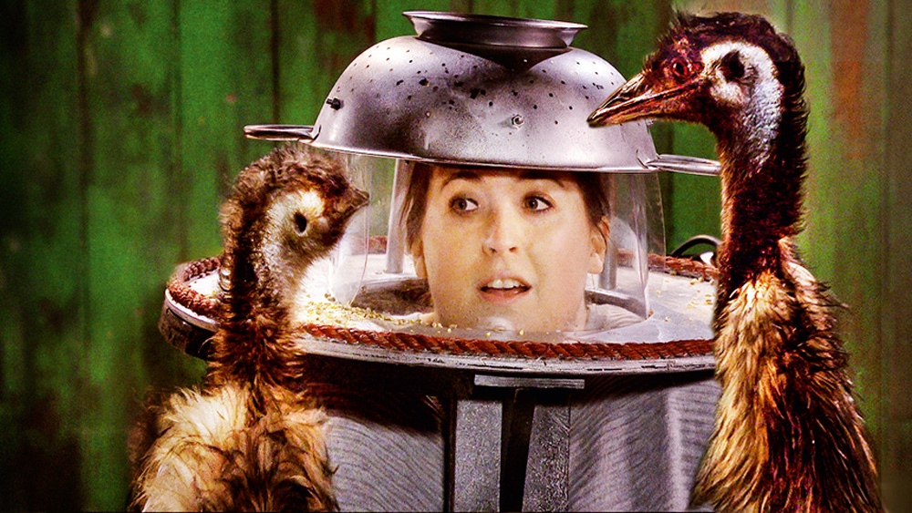 8 – Piscou, Dançou (DIVULGAÇÃO-NETFLIX).jpg Uma mulher vestida com equipamentos de cozinha na cabeça encara duas aves