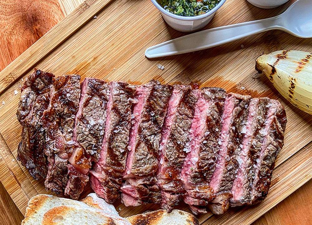 Uma fatia de bife ancho cortado em tiras e salpicado com sal sobre uma tábua