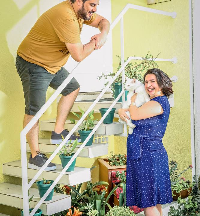 Daniel na escada olhando para baixo Tatiana segurando o gatinho da família, Max