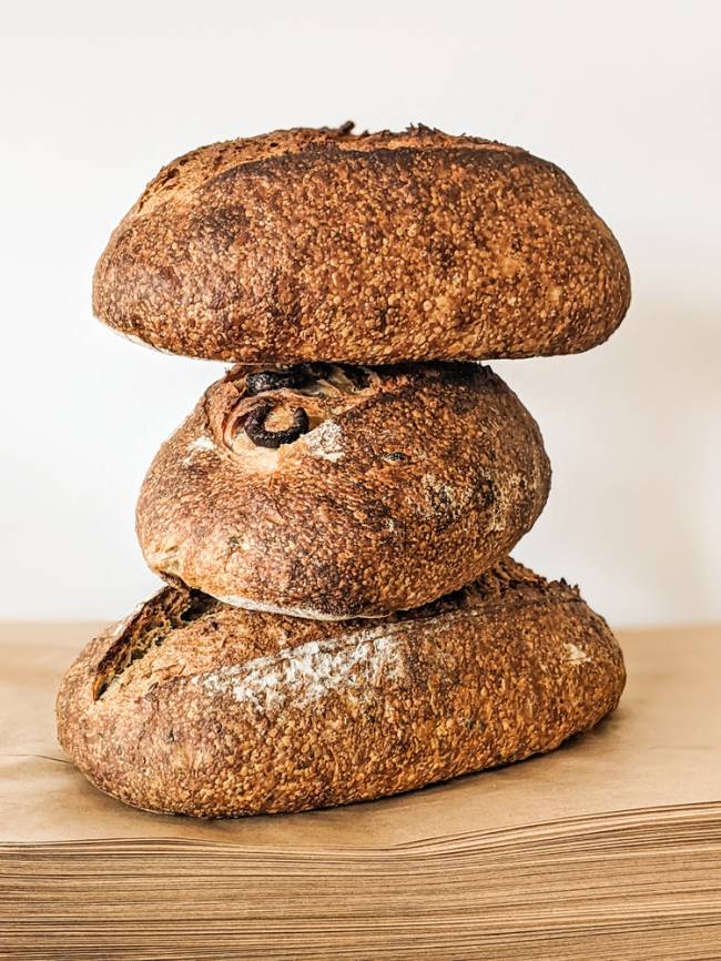 três pães assados., da cassa, de azeitonas e de grãos, empilhados 