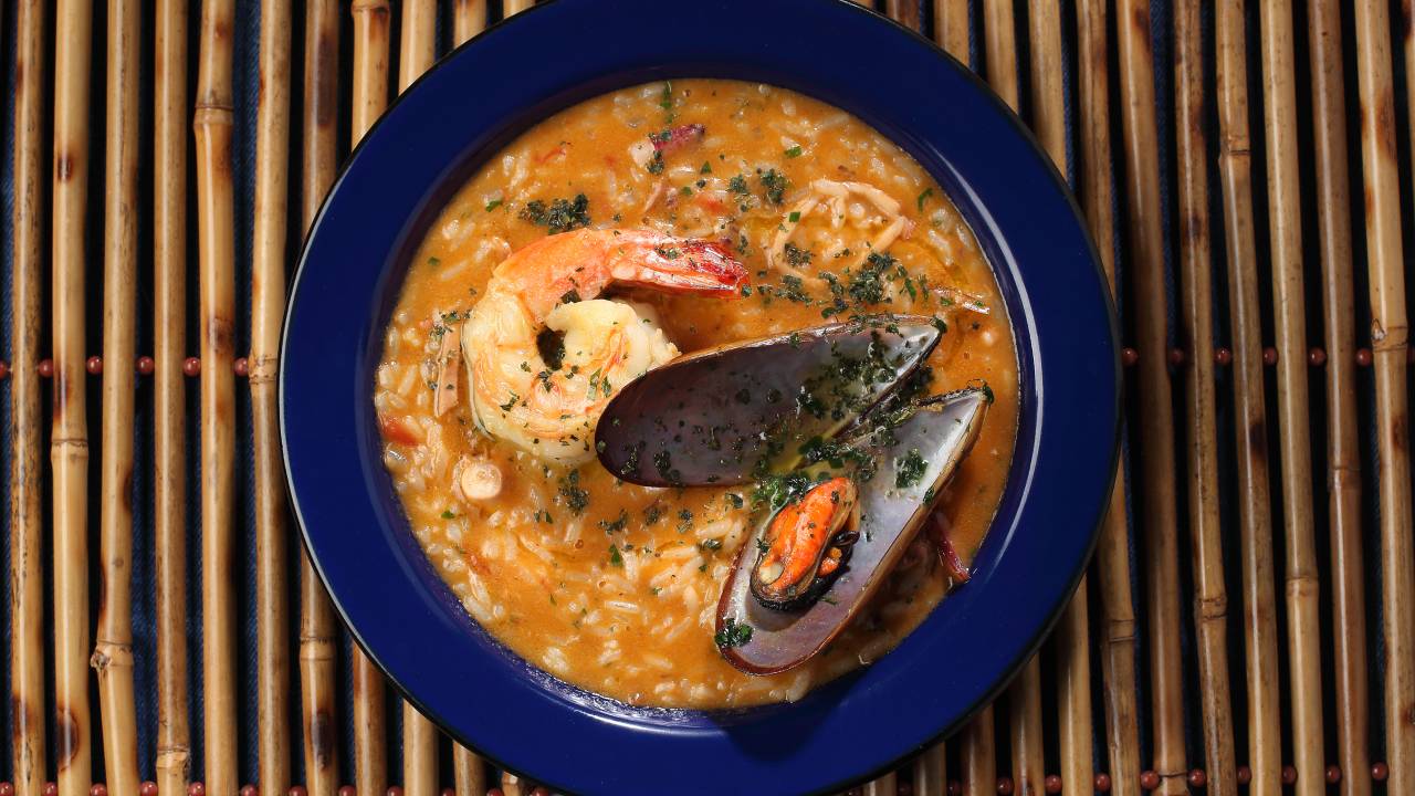 Prato da cor azul com arroz, polvo, camarão, lula, mexilhão e um toque de coentro